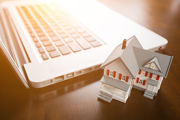 Image showing Miniature House And Laptop Computer Resting on Desktop.