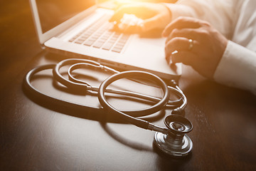 Image showing Medical Stethoscope Resting on Desk As Male Hands Type on Comput