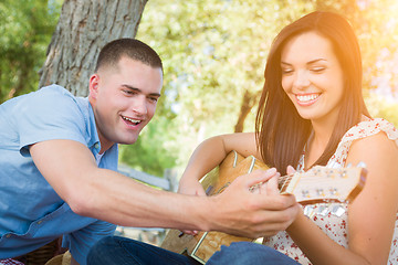 Image showing Handsome Young Man Teaching Mixed Race Girl to Play Guitar at th