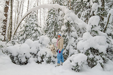 Image showing A woman with a dog in a snow-covered winter forest