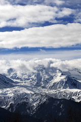 Image showing View on snow mountains and sunlight cloudy sky at winter day