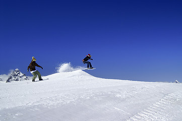 Image showing Two snowboarders jump in snow park at ski resort on sunny winter