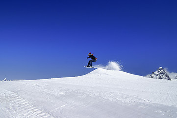 Image showing Snowboarder jumping in snow park at ski resort on sun winter day