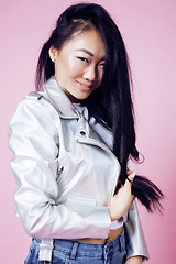 Image showing young pretty smiling asian korean girl wearing modern fashion clothers on pink background, lifestyle people concept 