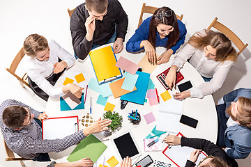 Image showing Team sitting behind desk, checking reports, talking. Top View