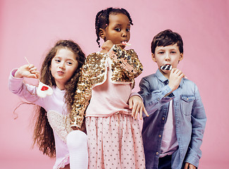 Image showing lifestyle people concept: diverse nation children playing together, caucasian boy with african little girl holding candy happy smiling 
