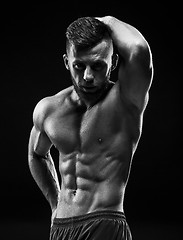 Image showing The torso of attractive male body builder on black background.