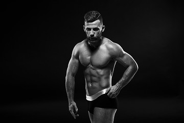 Image showing The torso of attractive male body builder on black background.