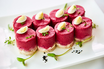 Image showing layered salad with herring, beets, carrots, onions, potatoes and eggs close-up on a plate. horizontal.