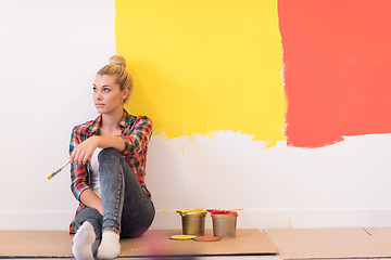 Image showing young female painter sitting on floor