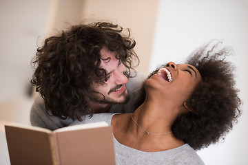 Image showing multiethnic couple hugging in front of fireplace