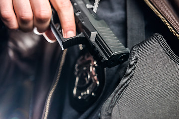 Image showing Closeup of police officer taking out handgun from holster at nig