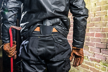 Image showing Midsection rear view of gangster with crowbar and gun standing b