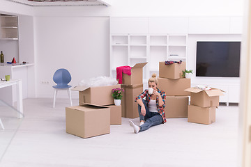 Image showing woman with many cardboard boxes sitting on floor