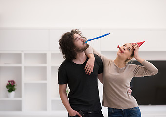 Image showing couple in party hats blowing in whistle