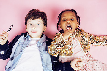 Image showing lifestyle people concept: diverse nation children playing together, caucasian boy with african little girl holding candy happy smiling 