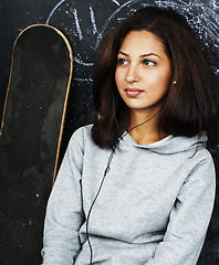 Image showing young cute teenage girl in classroom at blackboard seating on ta