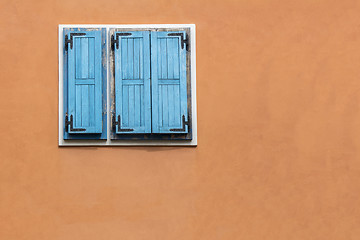 Image showing Blue wooden window shutters on the orange facade