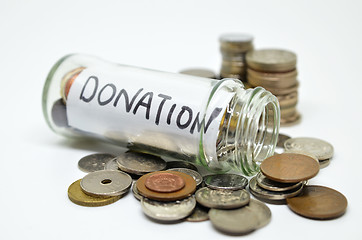 Image showing Donation lable in a glass jar with coins spilling out 