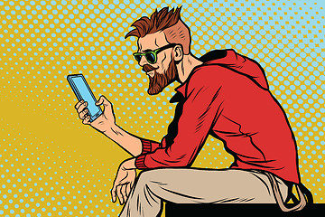 Image showing The hipster looks at smartphone