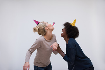 Image showing smiling women in party caps blowing to whistles