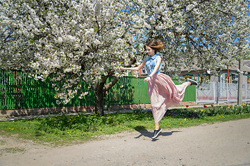 Image showing Young girl on the background of a blossoming cherry tree