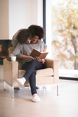 Image showing multiethnic couple hugging in front of fireplace