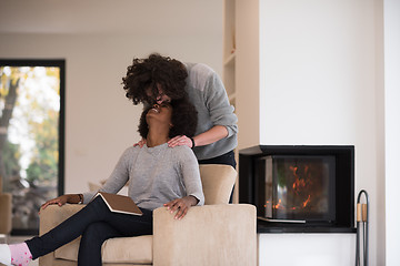 Image showing multiethnic couple hugging in front of fireplace