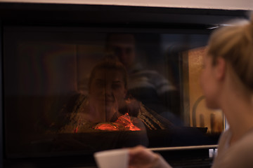 Image showing young woman drinking coffee in front of fireplace