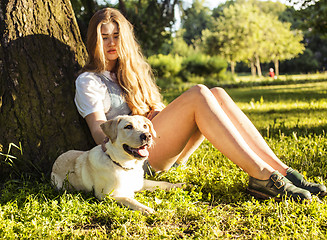 Image showing young attractive blond woman playing with her dog in green park 