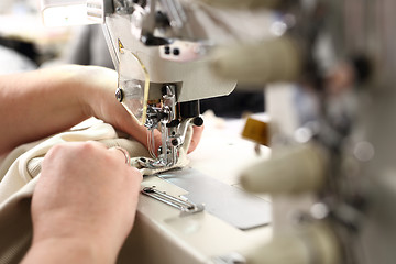 Image showing Sewing. Seamstress on the machine. Production of clothes, sewing on a machine