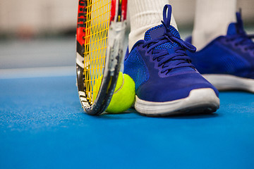 Image showing Legs of young girl in a closed tennis court with ball and racket