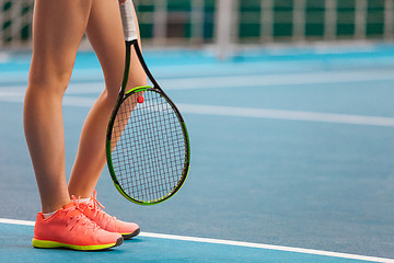 Image showing Legs of young girl in a closed tennis court with racket