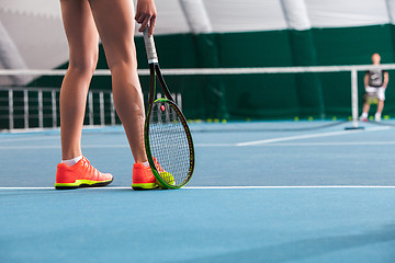 Image showing Legs of young girl in a closed tennis court with ball and racket