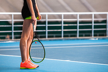 Image showing Legs of young girl in a closed tennis court with ball and racket