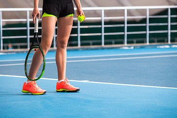 Image showing Legs of young girl in a closed tennis court with ball and racket