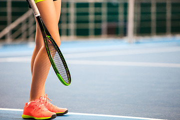 Image showing Legs of young girl in a closed tennis court with racket