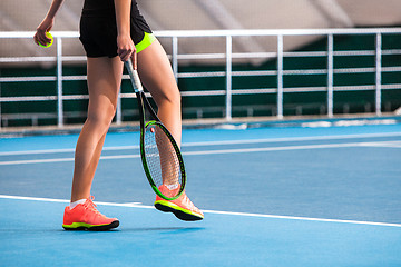Image showing Legs of young girl in a closed tennis court with ball and racket