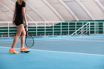 Image showing Legs of young girl in a closed tennis court with ball and racket