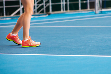 Image showing Legs of young girl in a closed tennis court with ball and racket