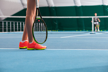 Image showing Legs of young girl in a closed tennis court with ball and racket