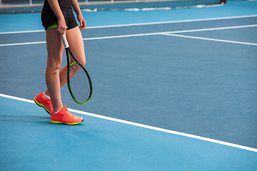 Image showing Legs of young girl in a closed tennis court with ball and racket