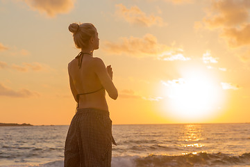 Image showing Woman practicing yoga on sea beach at sunset.