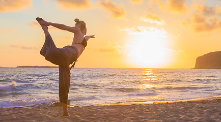 Image showing Woman practicing yoga on sea beach at sunset.