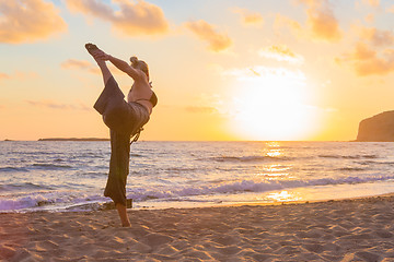 Image showing Woman practicing yoga on sea beach at sunset.