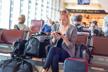 Image showing Female traveler using cell phone while waiting on airport.