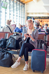 Image showing Female traveler using cell phone while waiting on airport.