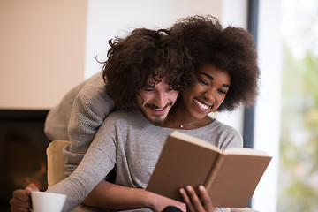 Image showing multiethnic couple hugging in front of fireplace