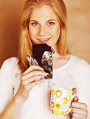 Image showing young cute blond girl eating chocolate and drinking coffee close