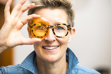 Image showing woman with glasses looking through orange glass